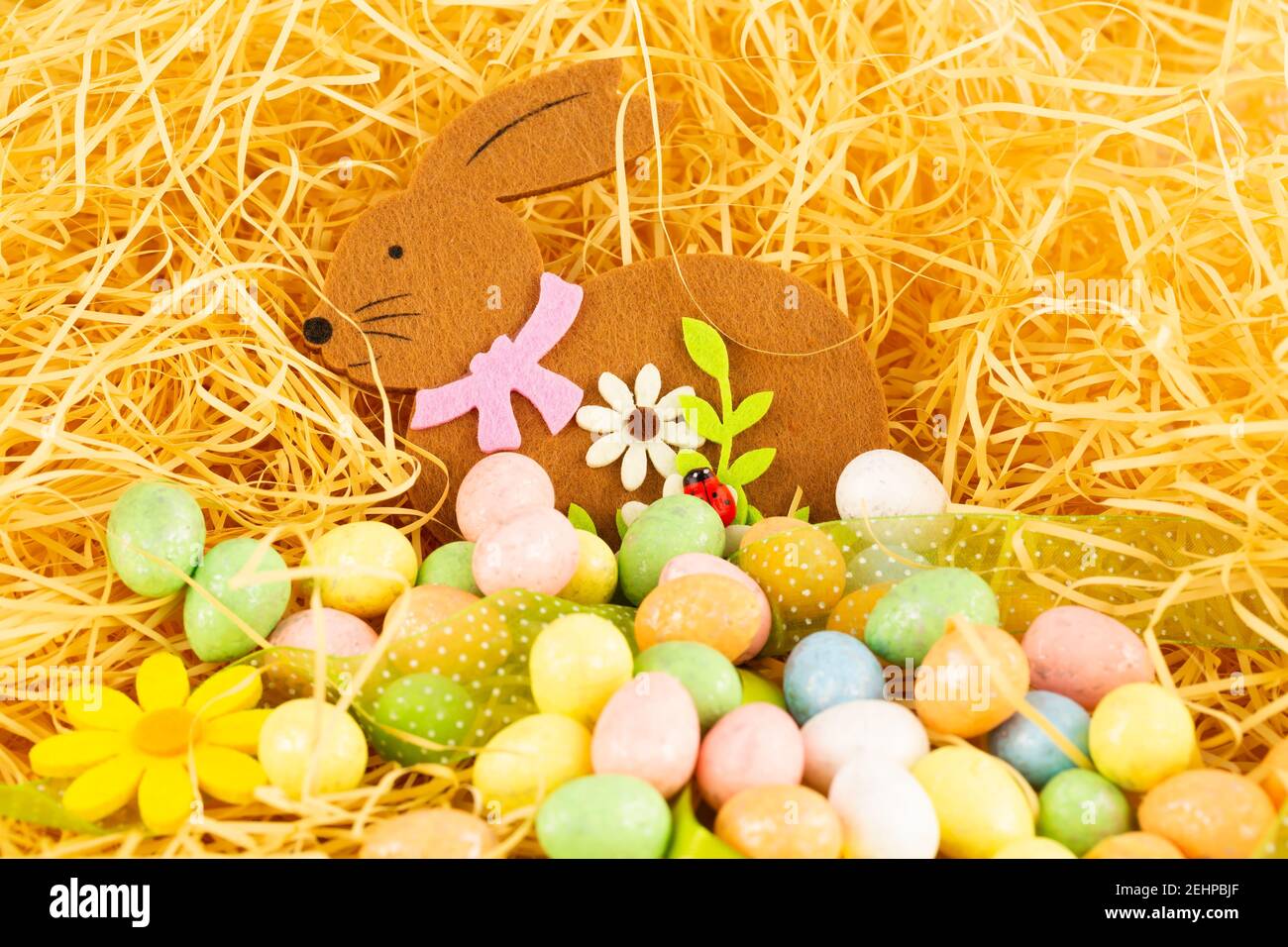 Easter bunny and colorful eggs on yellow straw background Stock Photo ...