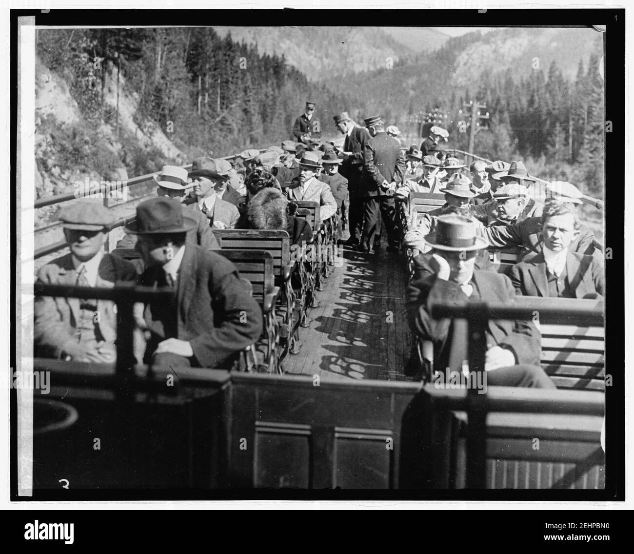 Passengers on roof deck of train traveling through mountains Stock Photo