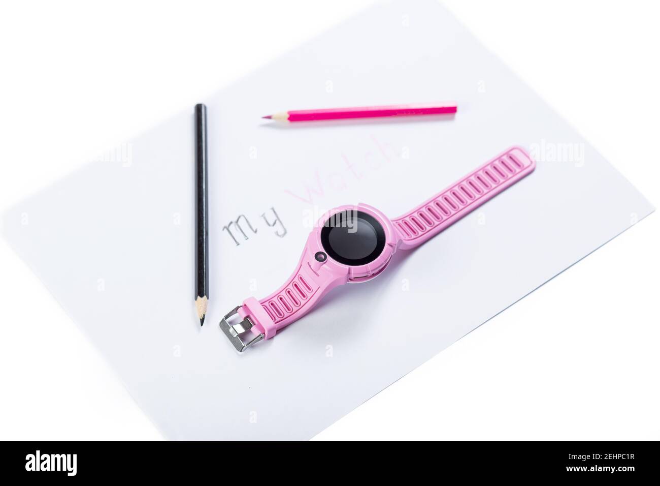 Pink samrt watch for kids, on piece of paper with pincils., isolated on a white. Stock Photo