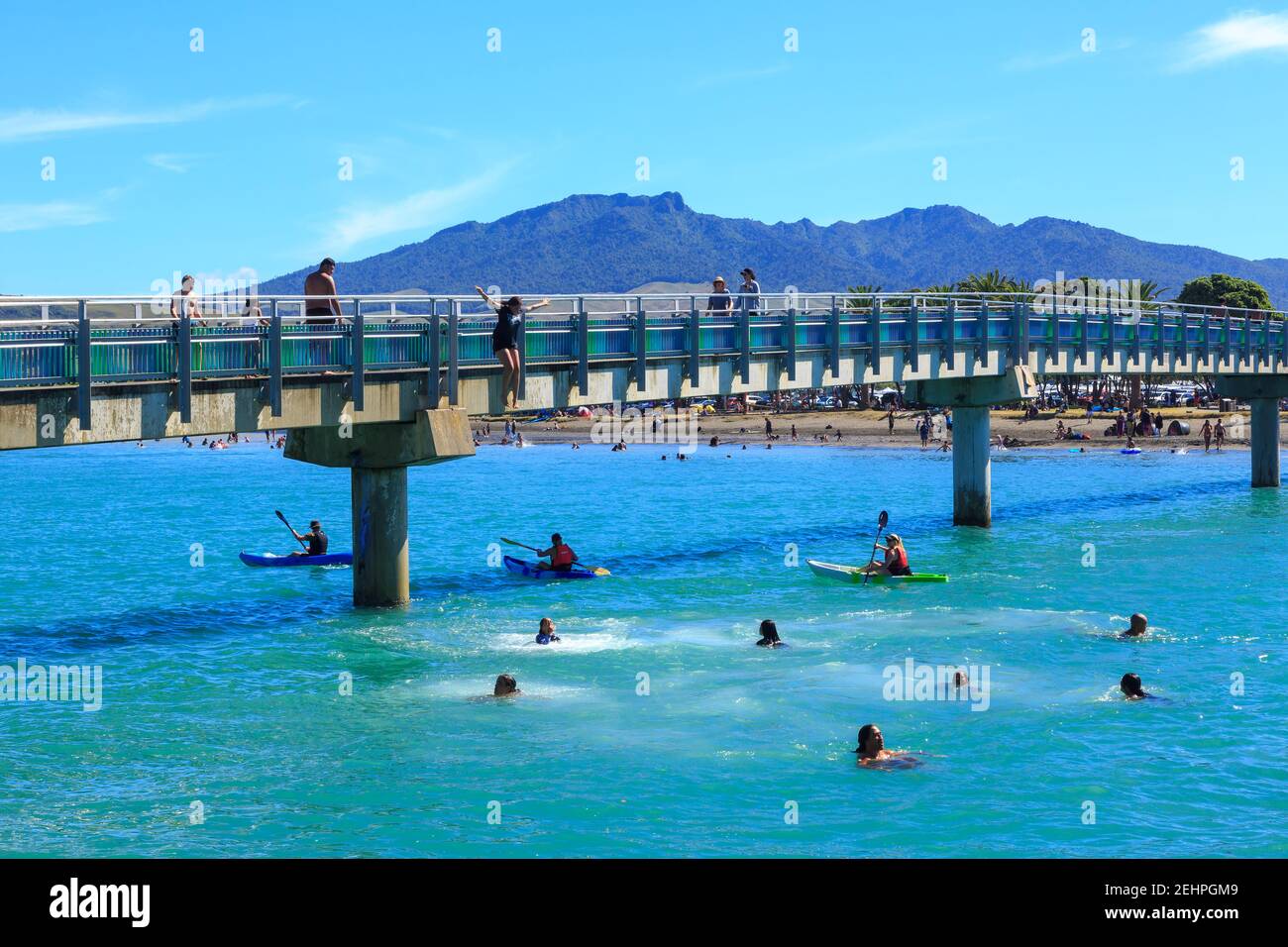 Raglan, New Zealand, in summer. Swimmers jumping into the harbor from the Te Kopua footbridge Stock Photo