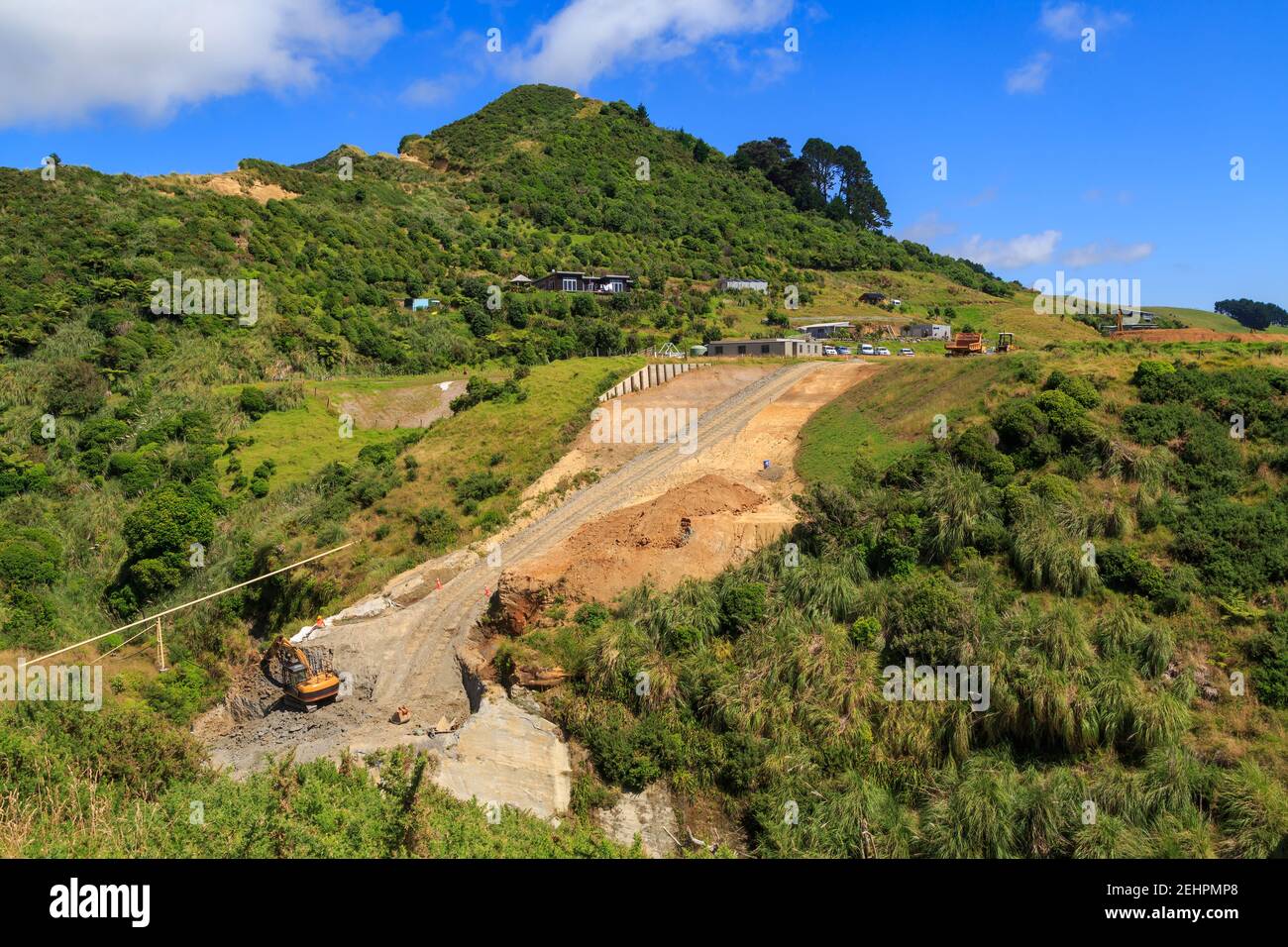 Road building on a rural hillside in New Zealand. An excavator is parked at the bottom of the construction site Stock Photo