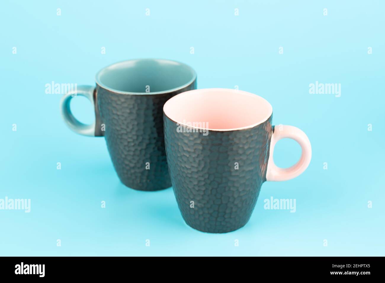 Two brown ceramic cups isolated on blue background. Stock Photo