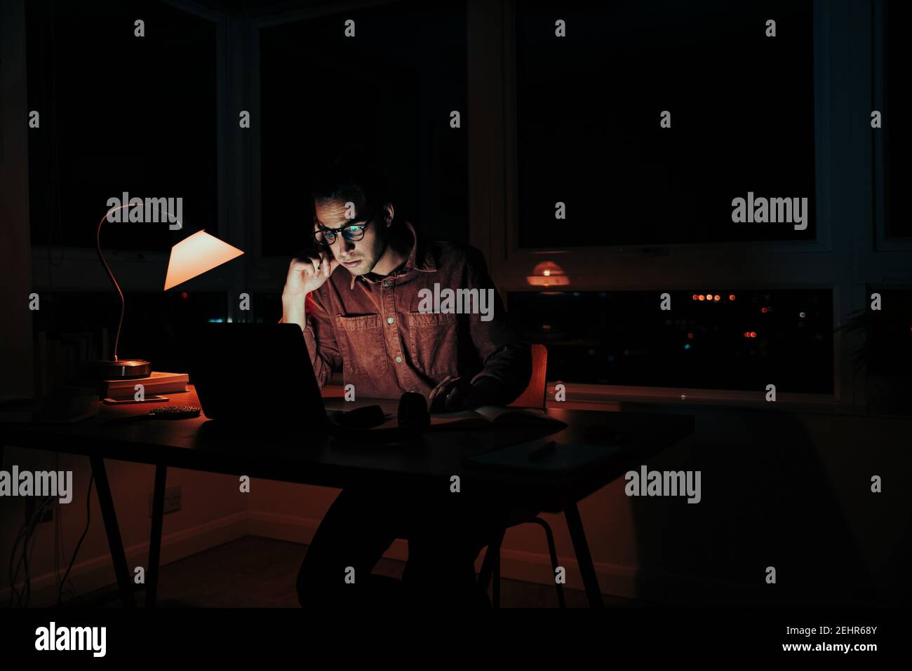 Caucasian male student working late at night stressed meeting deadlines sitting at home workspace Stock Photo