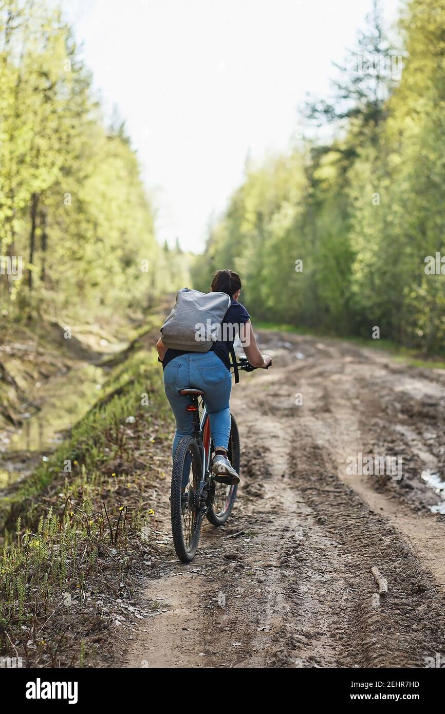 The female cyclist riding on her mountain bike on the forest path. Tires on the dirty forest road. Concept of choice mtb for riding on the loam. Stock Photo