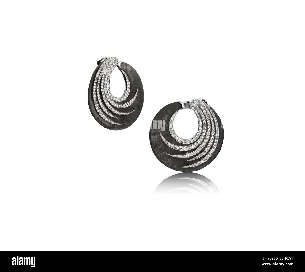 Precious diamond earrings on a shell-shaped frame in black metal. Studio shot isolated on white. Stock Photo