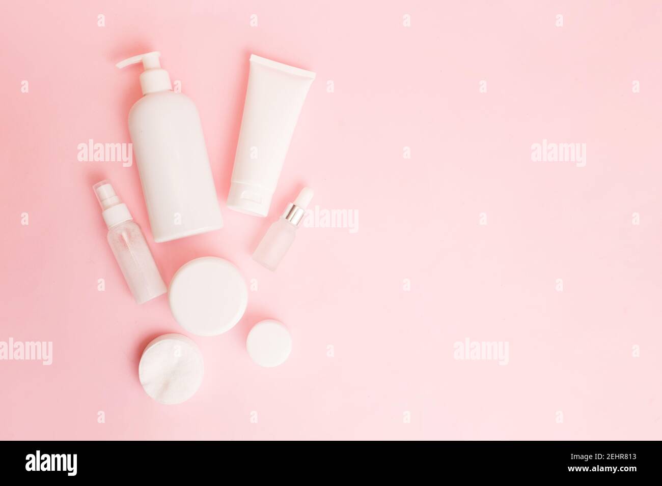 White jars of cosmetics on a pink pastel background. Bath accessories. Face and body care concept. Copy space, flat lay Stock Photo