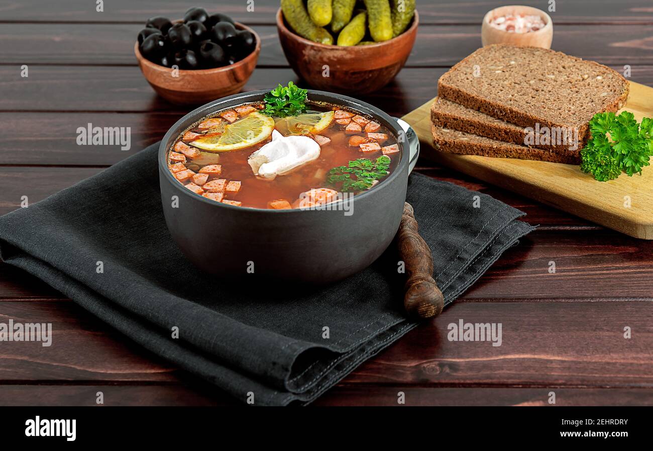 Solyanka or soljanka, russian and east european soup with sausage, olives, pickled cucumber, and capers Stock Photo