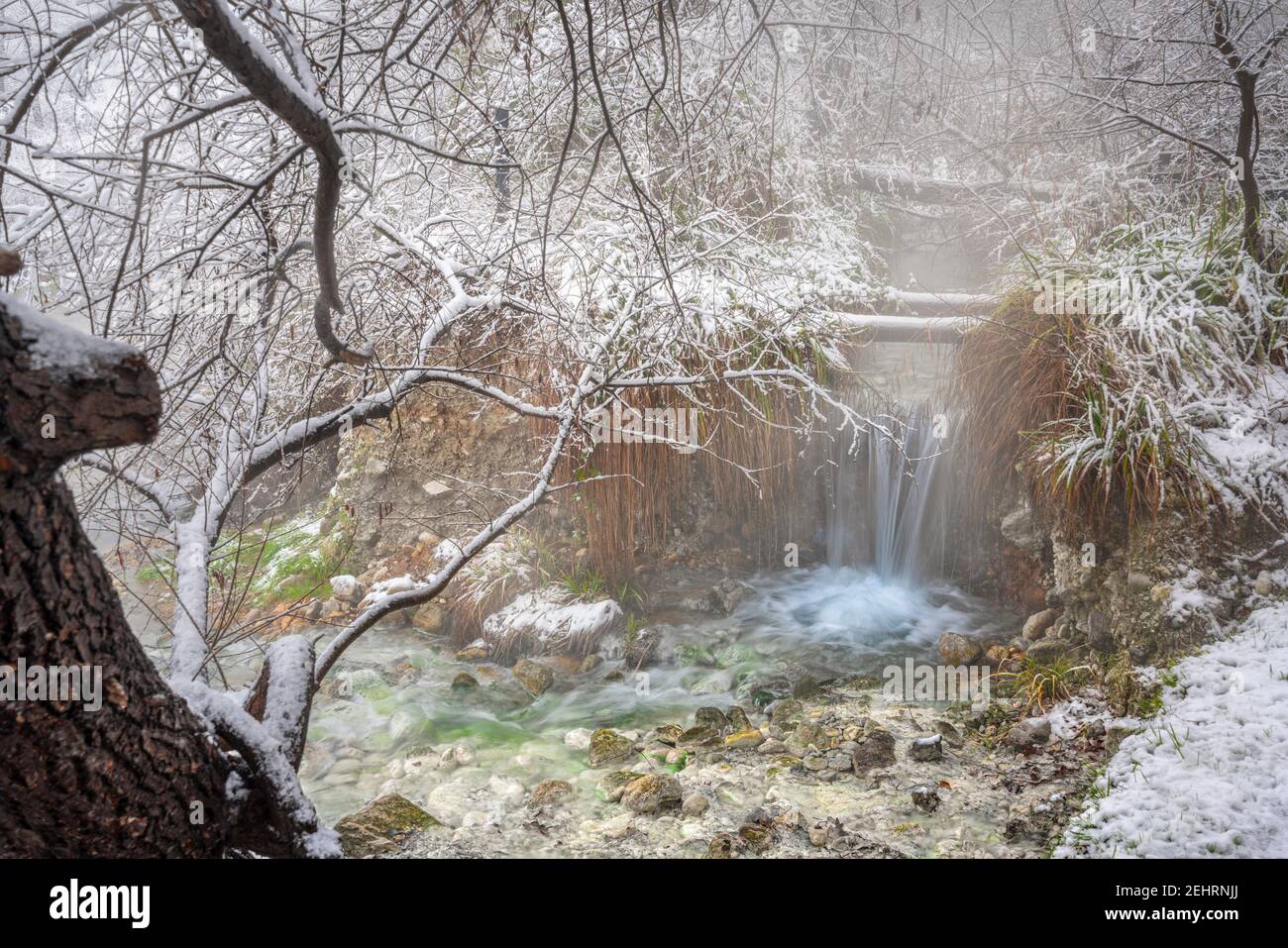 Waterfall of hot sulphurous water in a snowy landscape. Sources of the Lavino, Maiella National Park, Abruzzo Stock Photo