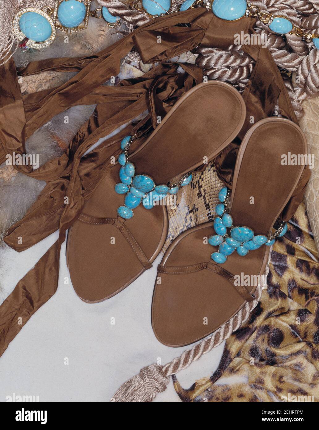 Composition of woman's flat sandal shoe, decorated with blue stones. Necklace with blue stones and silk leopard scarf. Stock Photo