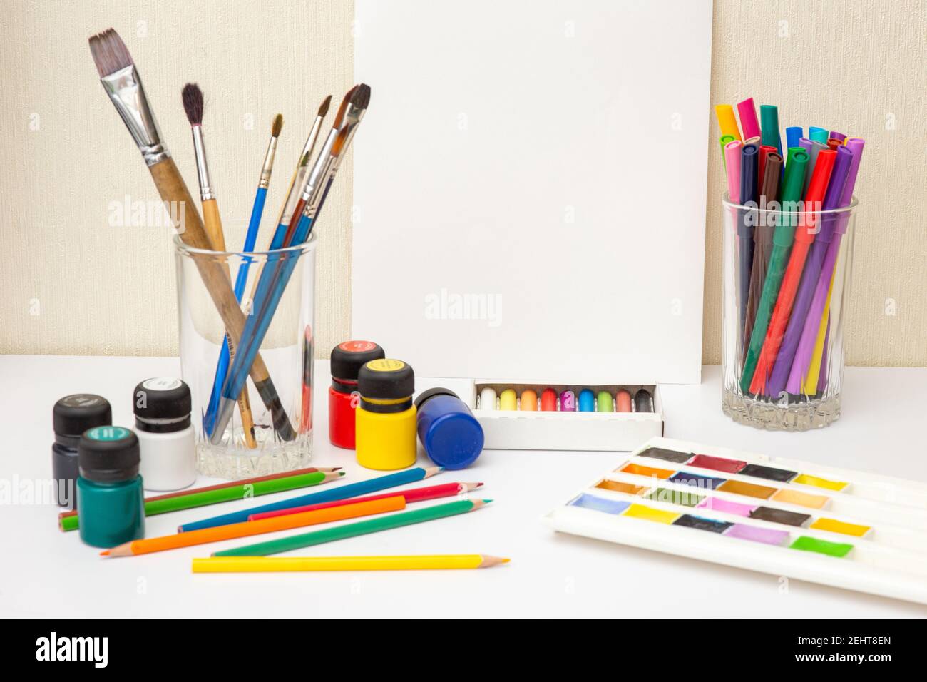 Paintbrushes and colorful drawing supplies on white table. Mock up