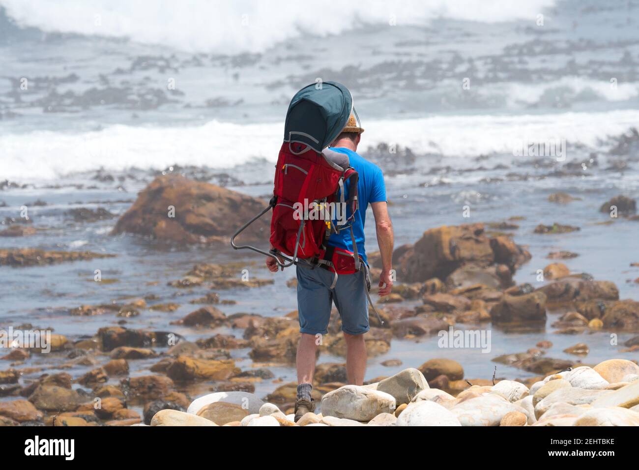 man carrying a baby in a baby carrier backpack at the sea concept gender equality and parenting, authentic lifestyle Stock Photo