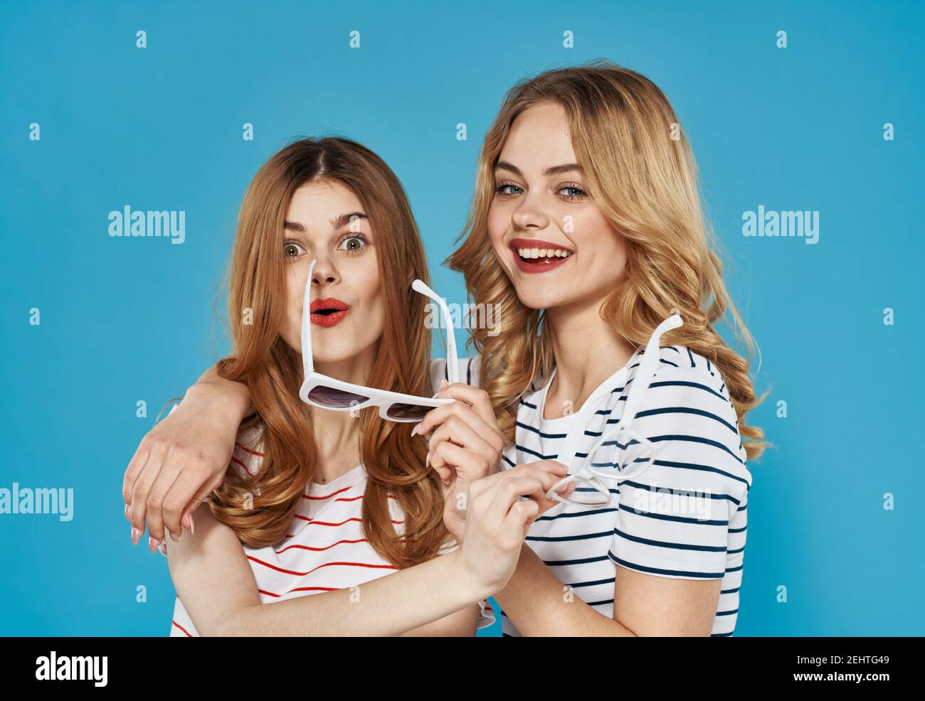 two mature women in trendy clothes striped t-shirts cropped blue background  chatting Stock Photo - Alamy