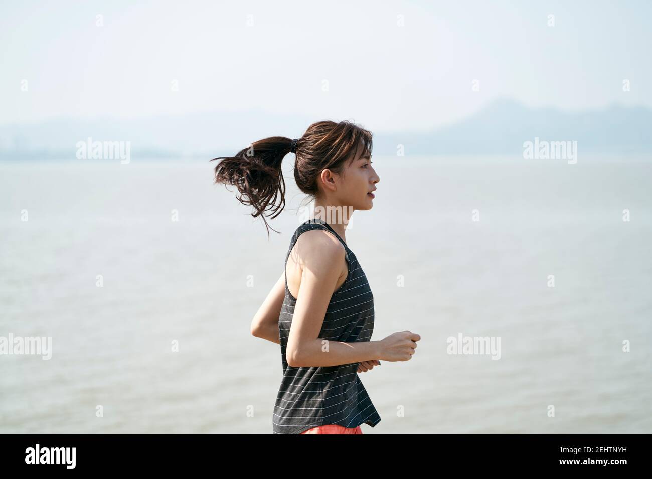 young asian woman female runner running by the sea, black and white Stock Photo