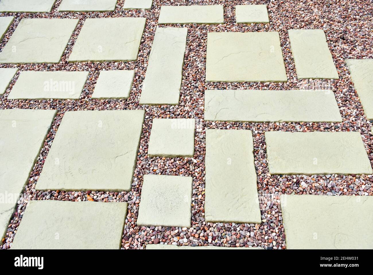 A lovely patio area with light coloured stone slabs and gravel with pinkish tones in an asymmetric pattern Stock Photo