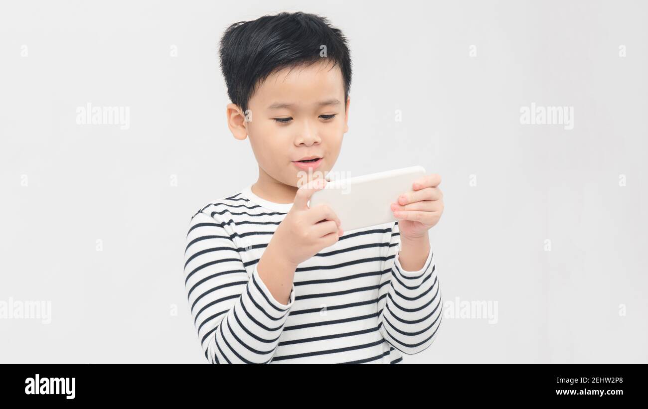 Asian child focused and concentrated playing with mobile phone  in kid suffering gaming addiction concept Stock Photo