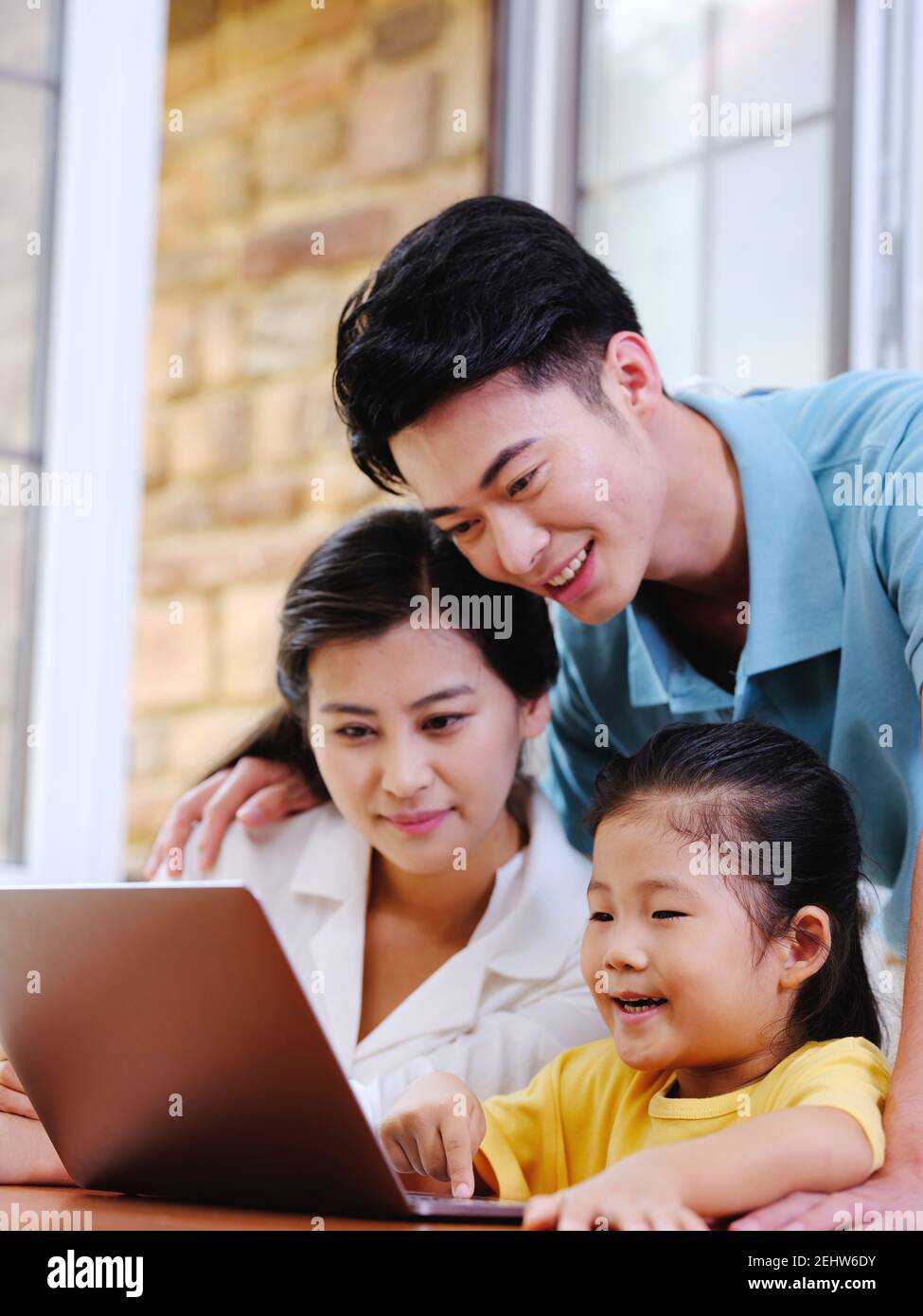 Happy family of three using laptop in the house Stock Photo