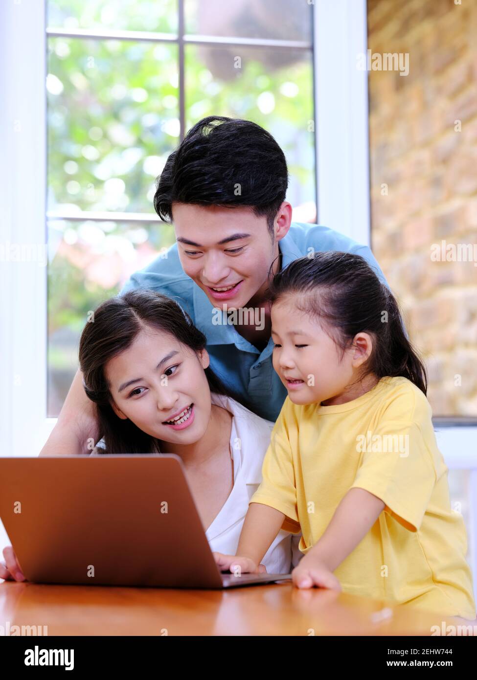 Happy family of three using laptop in the house  Stock Photo