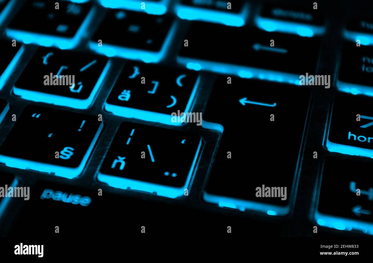 Modern blue iluminated backlit keyboard.Blue backlight, backlit on laptop or keyborad computer of gaming in the dark.Paused game. Cyber Attack concept. Stock Photo