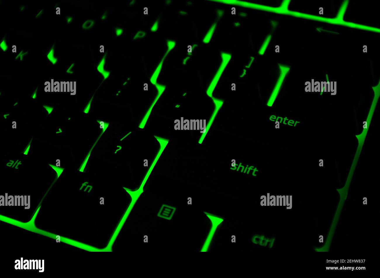 Modern green iluminated backlit keyboard. Green backlight, backlit on keyborad computer of gaming in the dark. Cyber Attack, hacking concept. Stock Photo