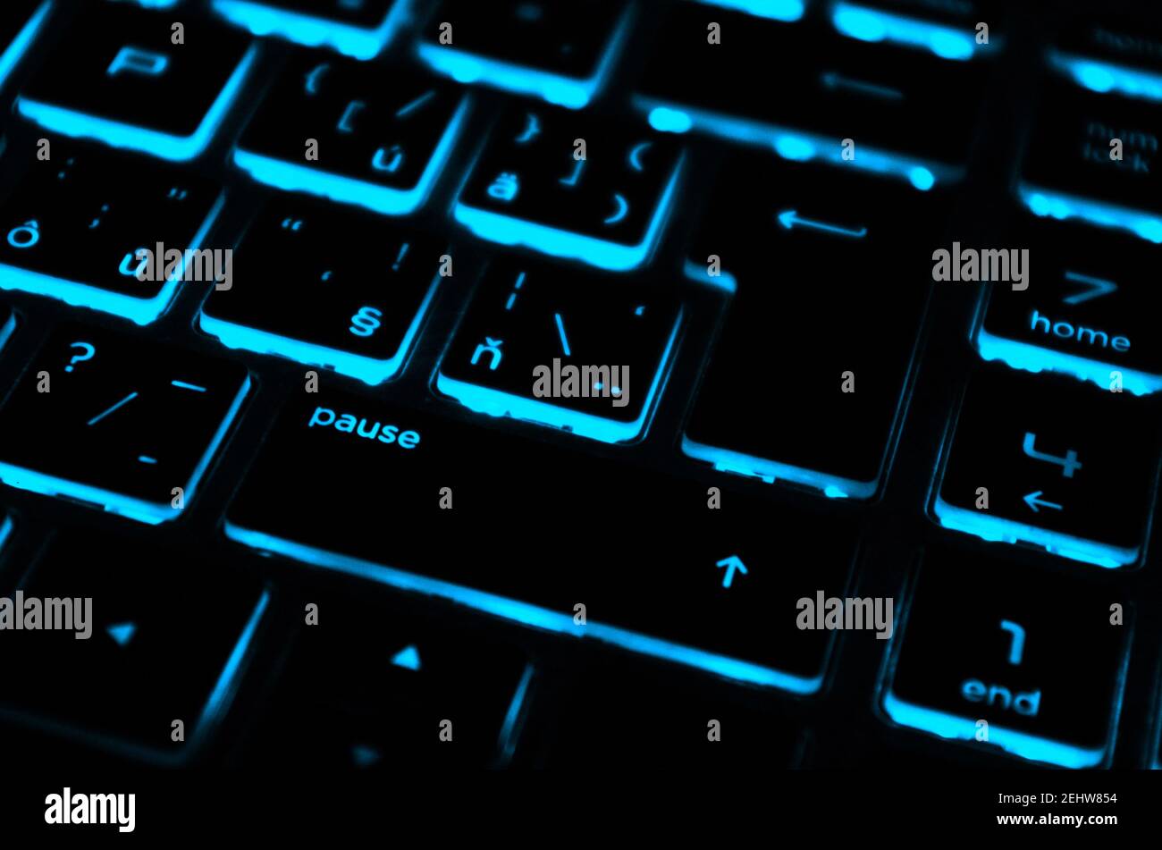 Modern blue iluminated backlit keyboard.Blue backlight, backlit on laptop or keyborad computer of gaming in the dark.Paused game. Cyber Attack concept. Stock Photo