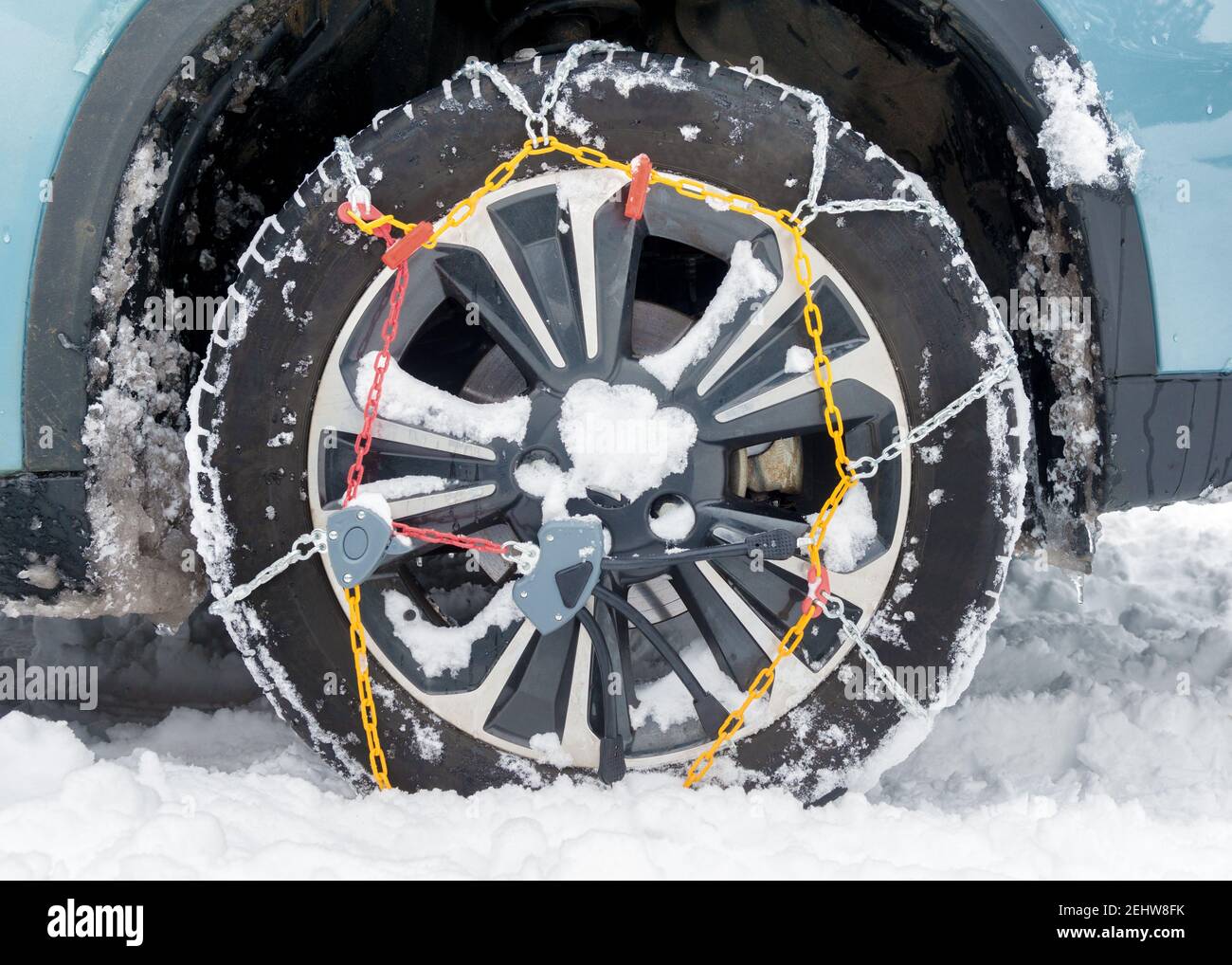 snow chains fitted on a car wheel in winter Stock Photo