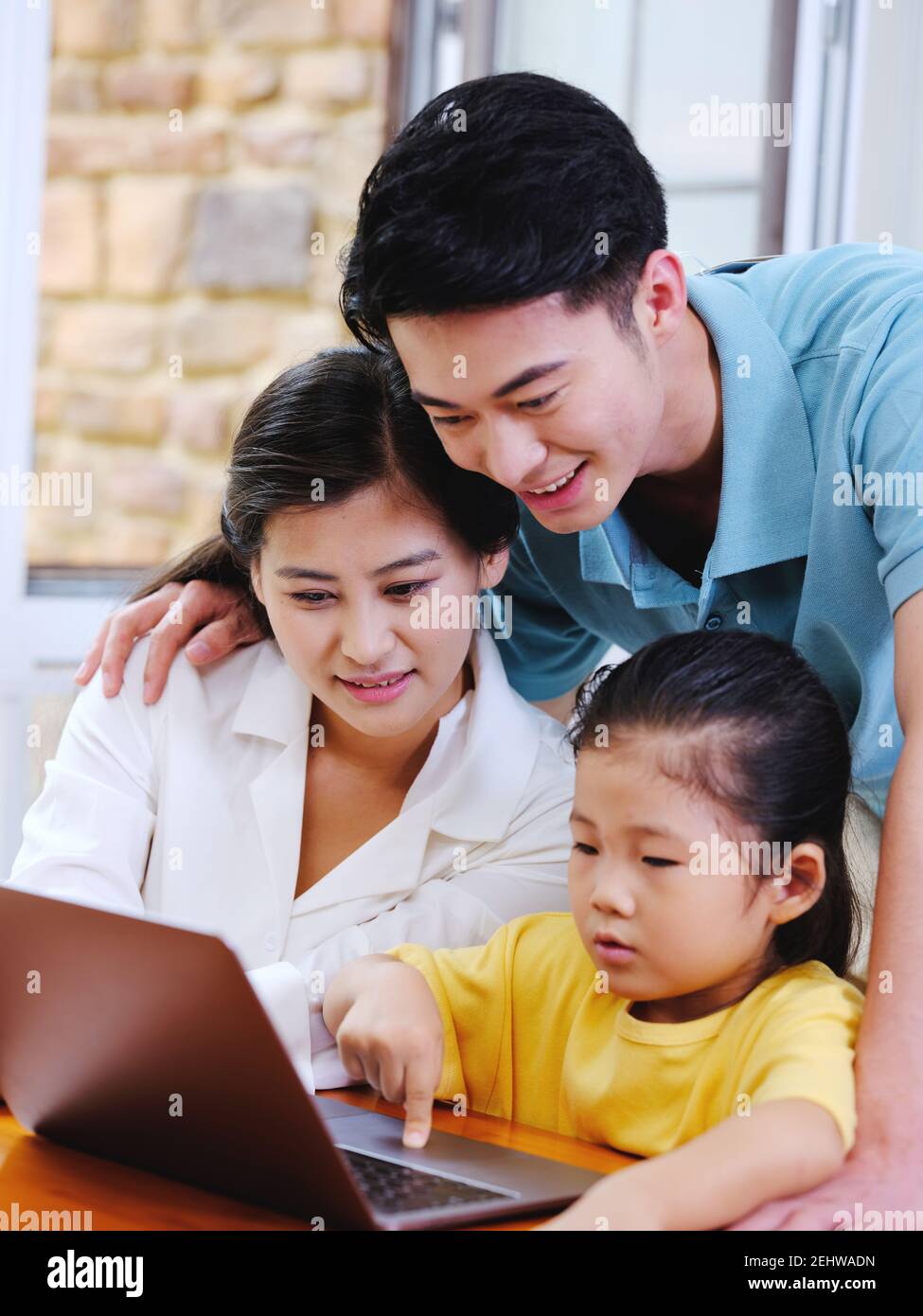 Happy family of three using laptop in the house  Stock Photo