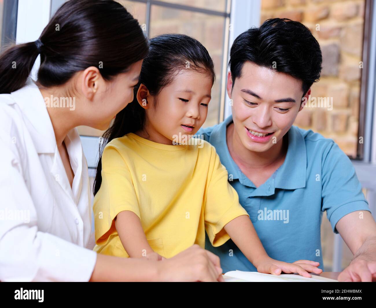 Happy family of three reading and writing together Stock Photo Alamy