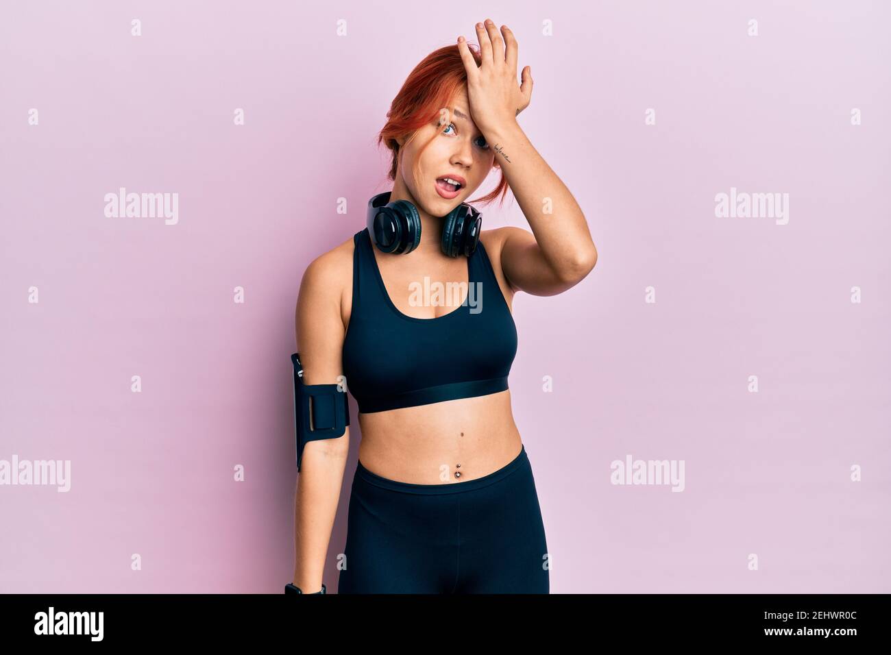 Young beautiful redhead woman wearing gym clothes and using headphones