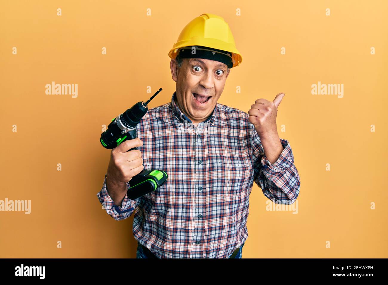 Handsome senior man with grey hair holding electric screwdriver wearing ...