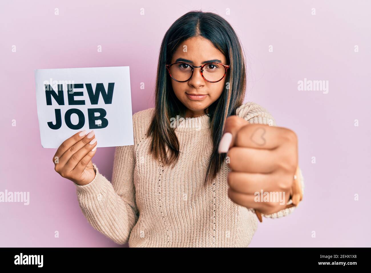 Young latin girl holding new job message on paper annoyed and ...
