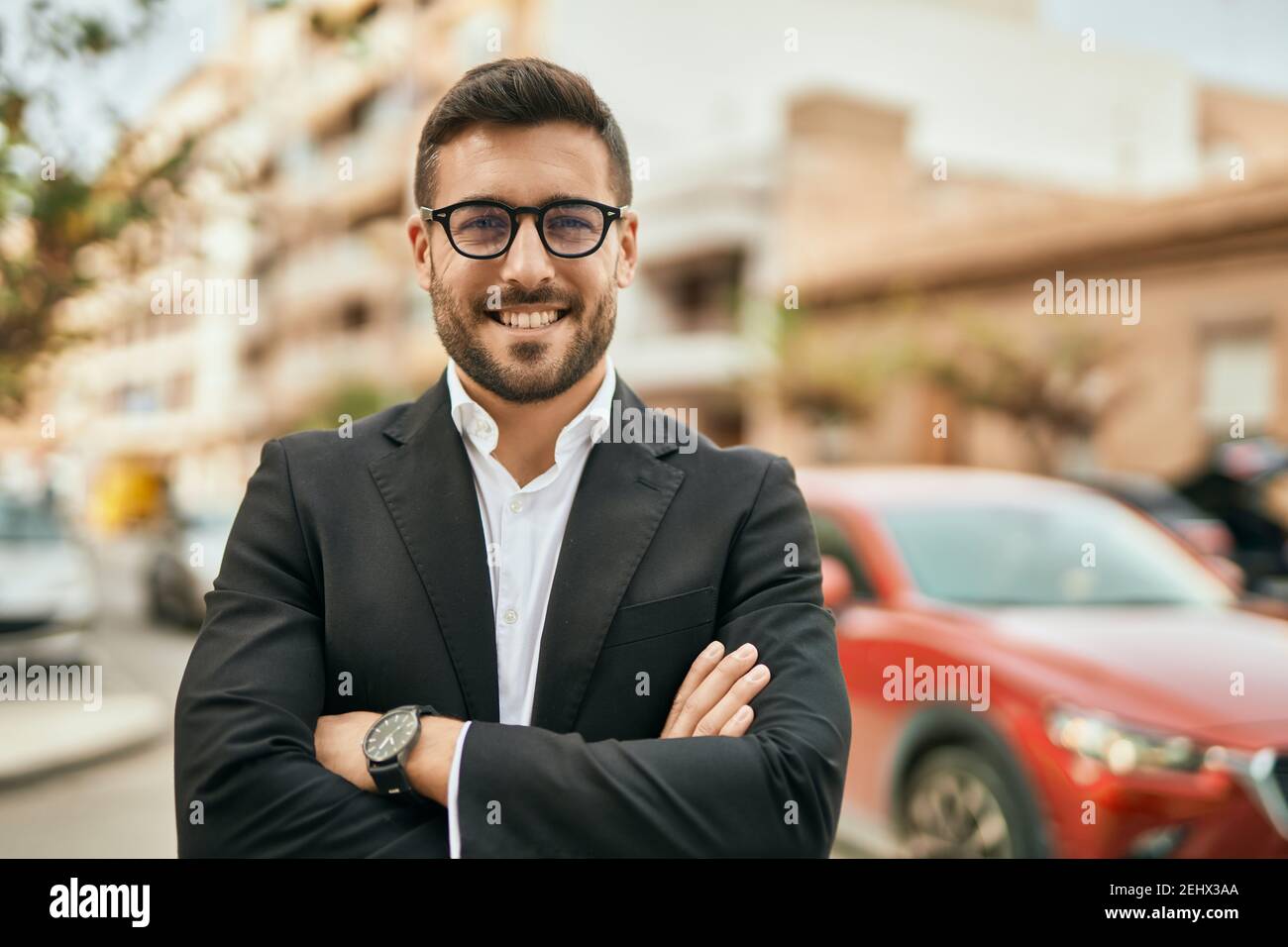 Young hispanic businessman with arms crossed smiling happy at the city ...
