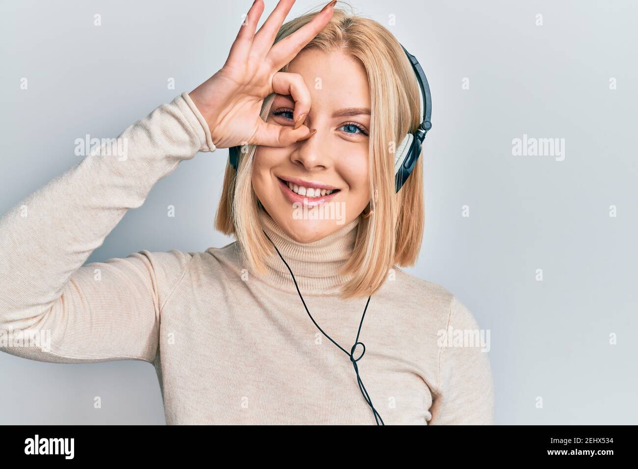 Young blonde woman listening to music using headphones smiling happy ...