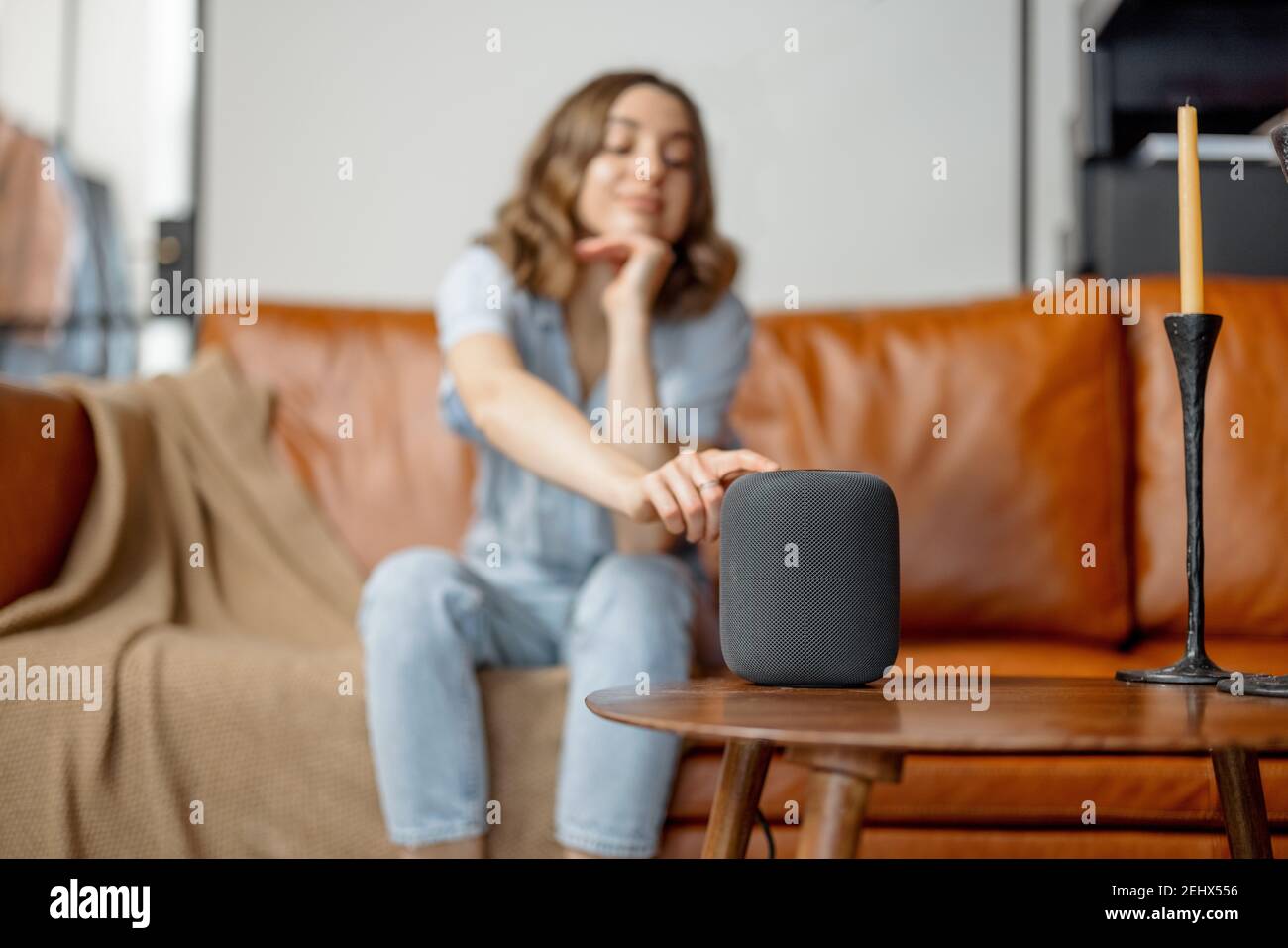 Woman touching black audio assistant column on the coffee table Stock Photo