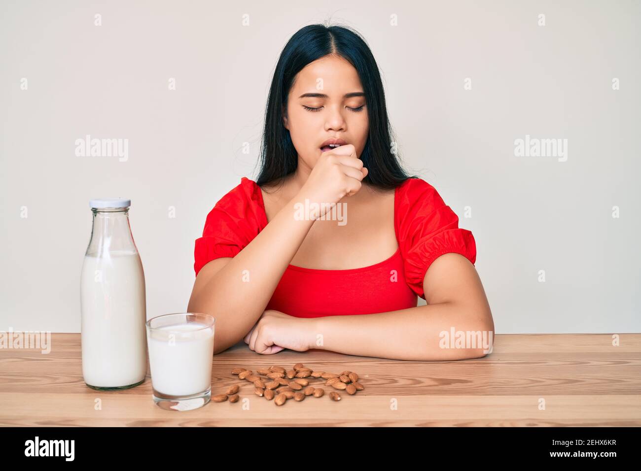 Young asian girl drinking healthy almond milk feeling unwell and