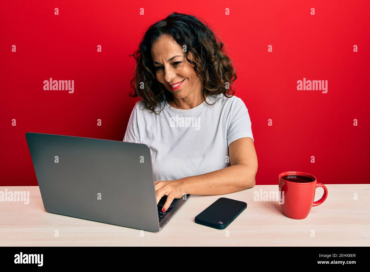 Beautiful middle age woman working at the office using computer laptop ...