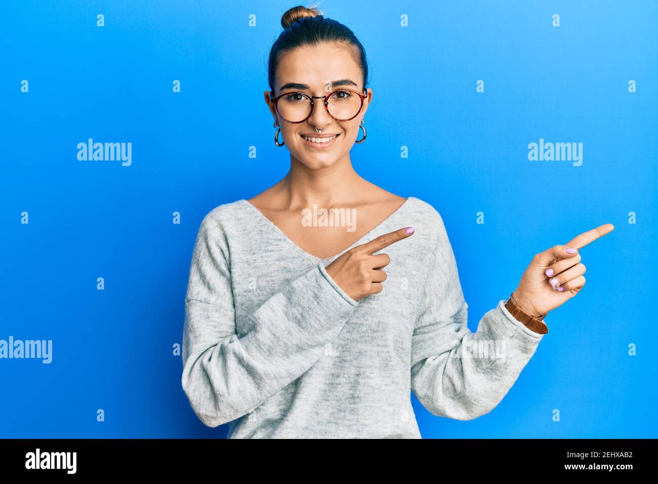 Young hispanic woman wearing casual clothes smiling and looking at the camera pointing with two hands and fingers to the side. Stock Photo