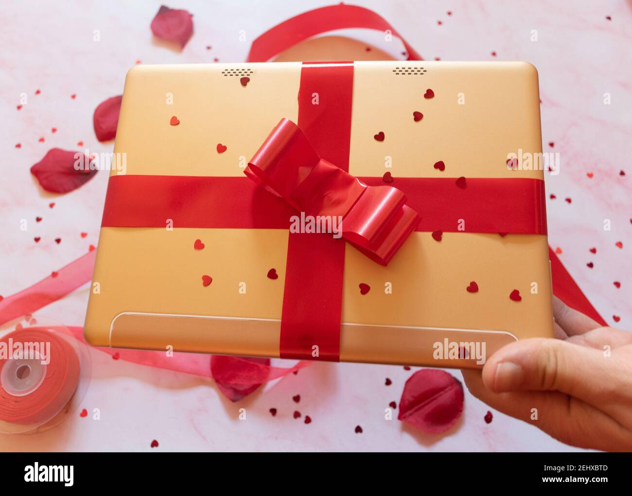 gift wrapped tablet with red bow and background ornaments Stock Photo