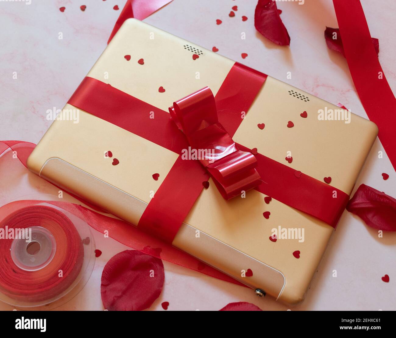 gift wrapped tablet with red bow and background ornaments Stock Photo