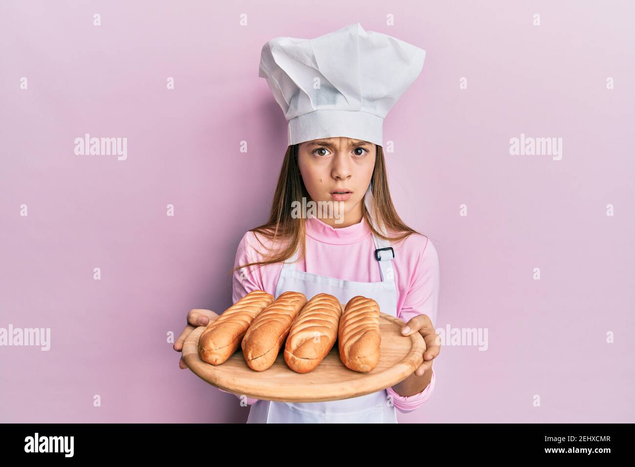 Beautiful brunette little girl wearing baker uniform holding homemade ...