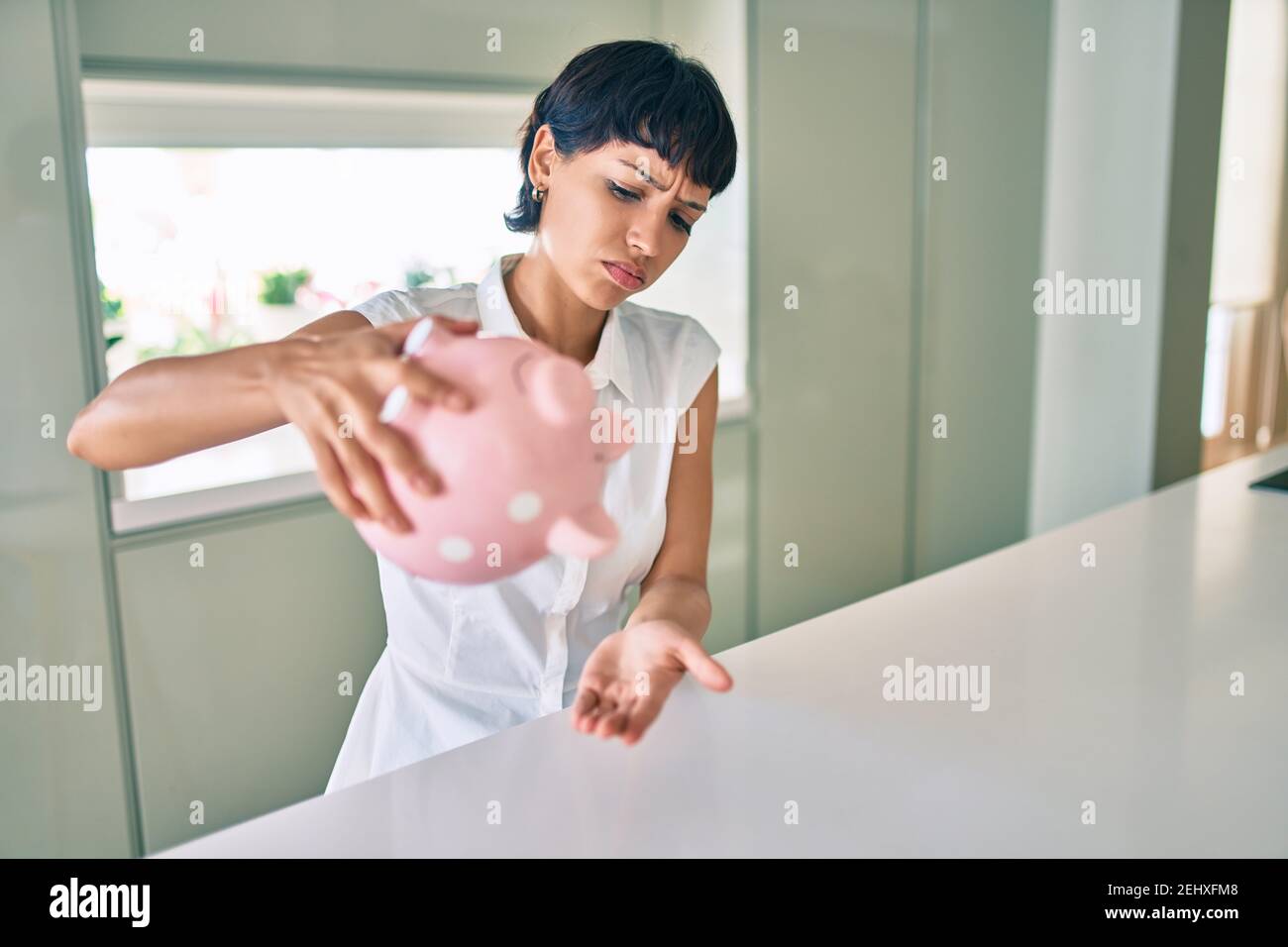 Young brunette woman showing empty piggy bank with sad face Stock Photo