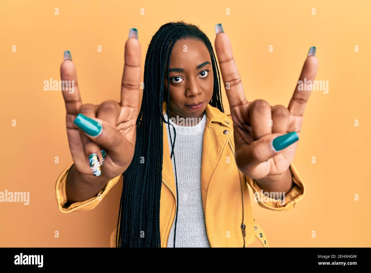 Young african american woman doing rock gesture skeptic and nervous ...