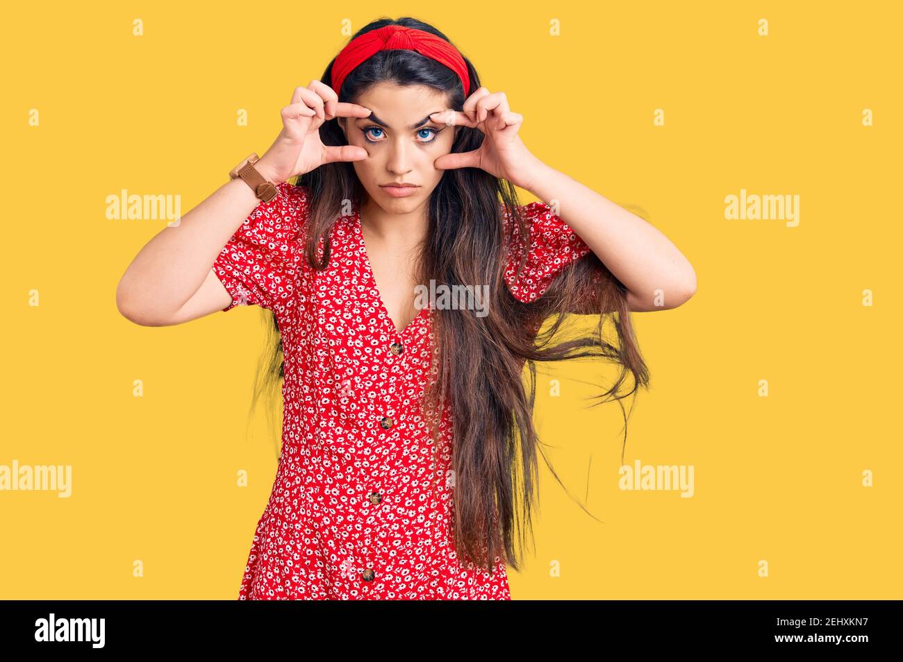 Brunette teenager girl wearing summer dress trying to open eyes with fingers, sleepy and tired for morning fatigue Stock Photo
