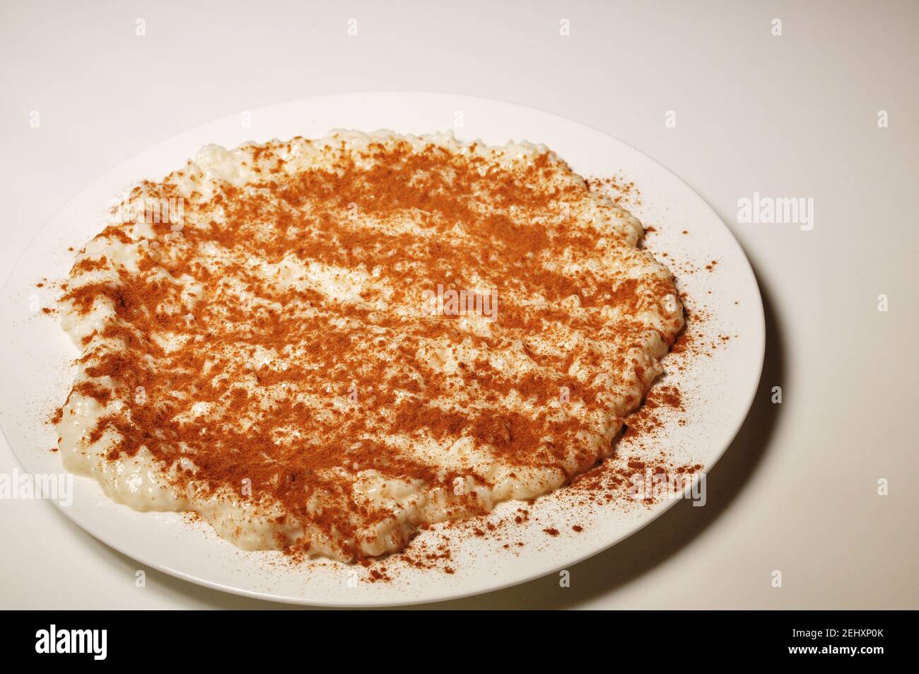 Milk with rice and cinnamon on white plate Stock Photo