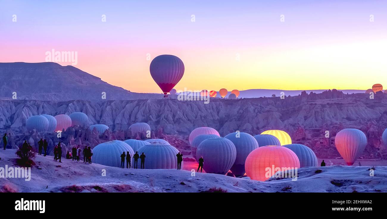 Raising hot air balloons in Cappadocia at sunrise, gorizontal panorama. Stock Photo