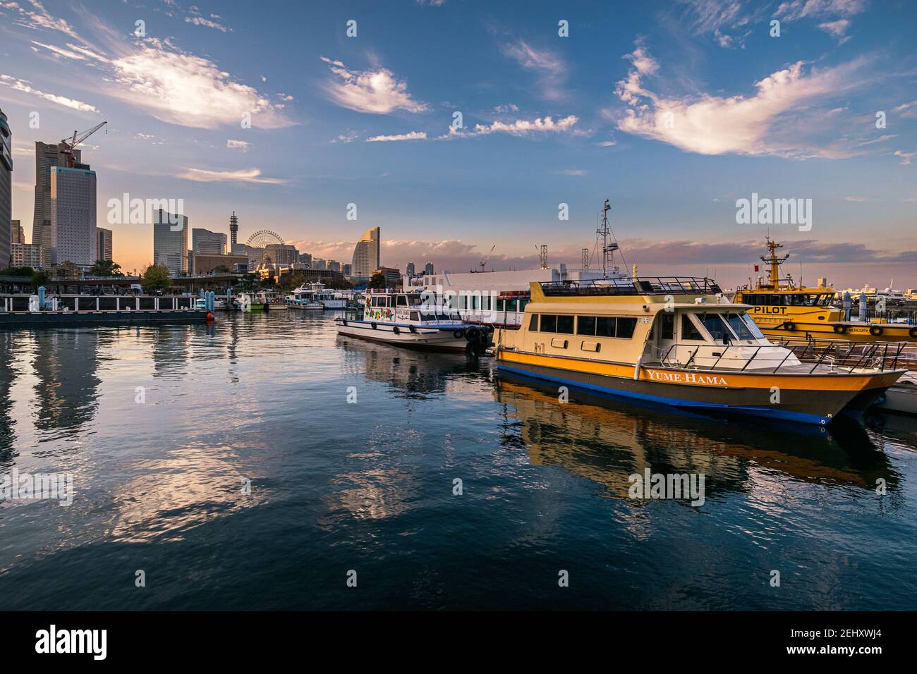 Boats docked at sunset at one of the piers in the Yokohama Ferry Terminal area. Stock Photo