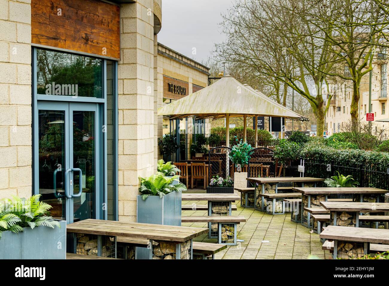 An empty pub beer garden during the covid19 lockdown in London, UK. Patio heaters and wooden bench and tables surrounded by green plants. Stock Photo