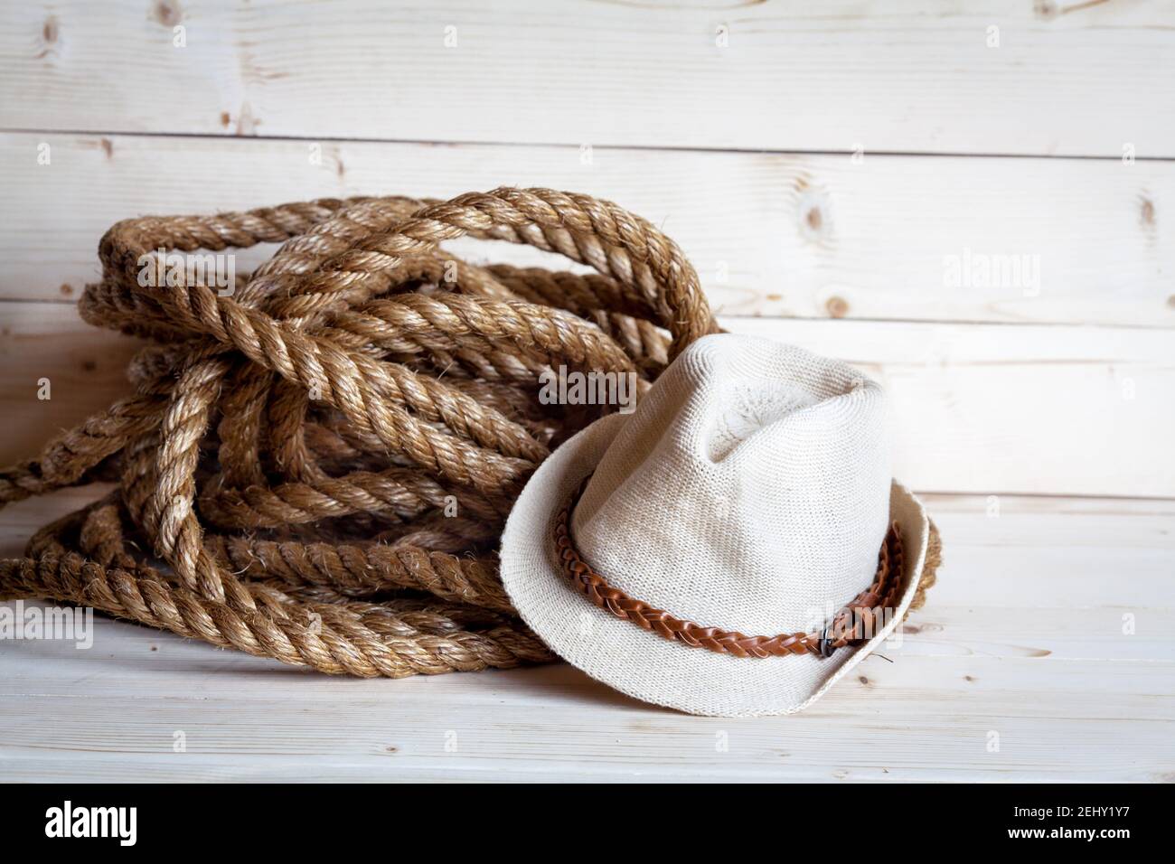 rope and women's straw hat in cowboy style on the wooden background and Stock Photo