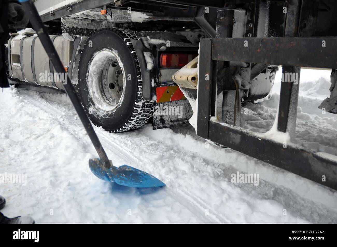 A heavy car got stuck in the snow on the road. Dig it out when looking for a shovel. Stock Photo