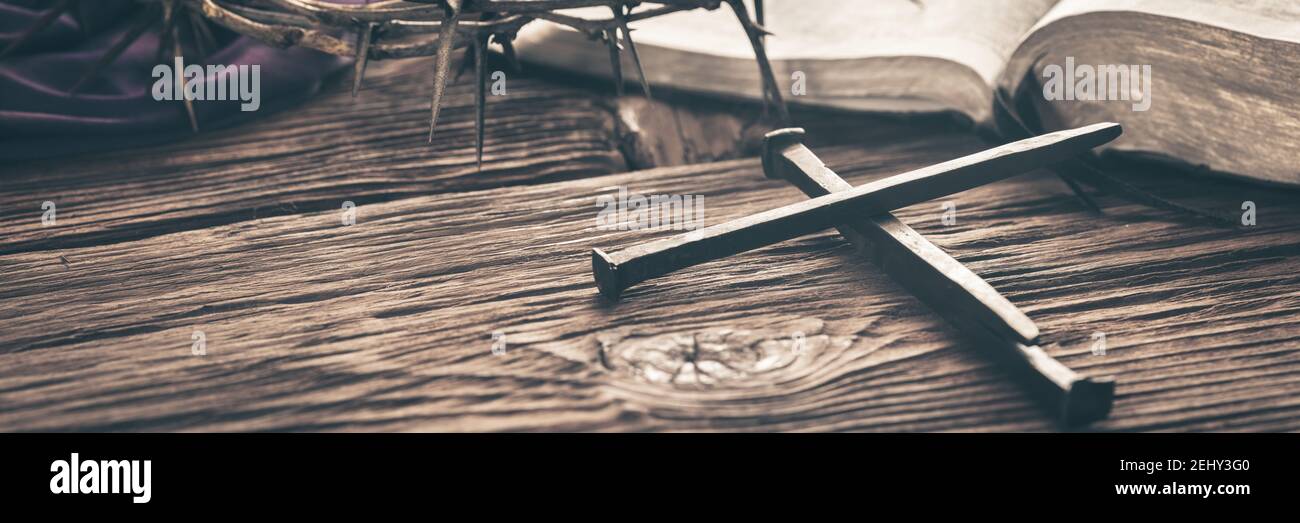 Three Crucifixion Spikes In Shape Of Cross On Wooden Table With Bible, Crown Of Thorns And Purple Robe With Vintage Effect - Crucifixion And Resurrect Stock Photo