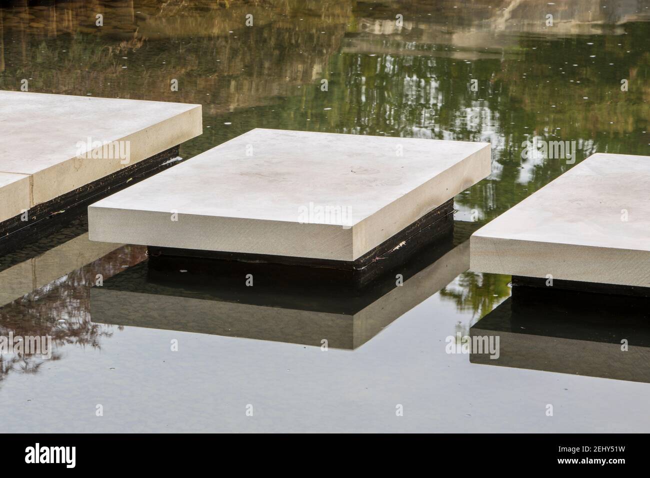 Floating stone stepping stones paving slabs over a pond water feature - A Japanese Reflection garden Stock Photo